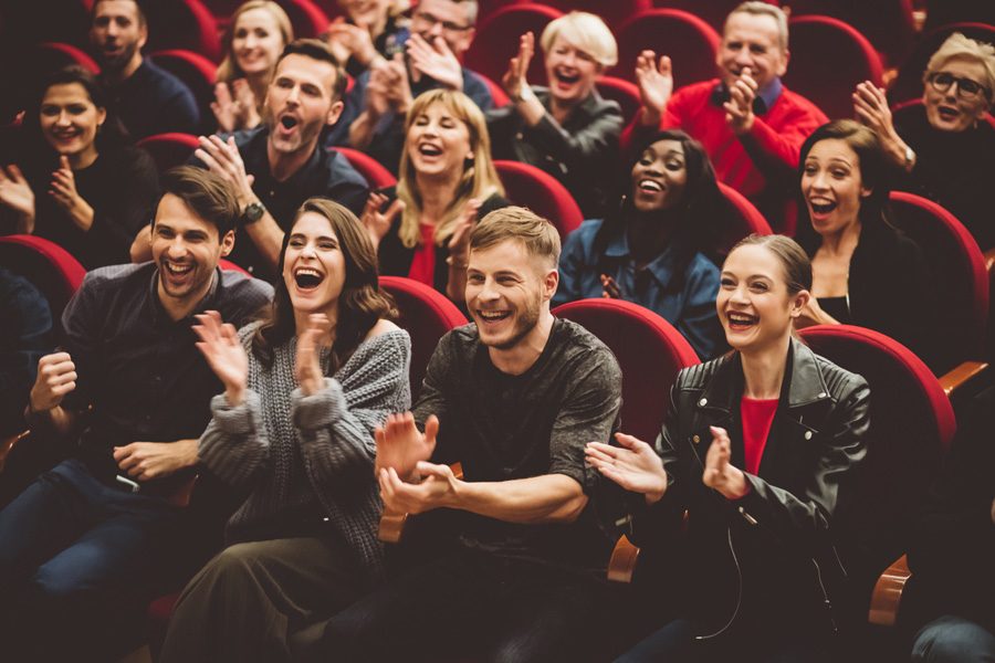 Group of excited people clapping hands in the theatre